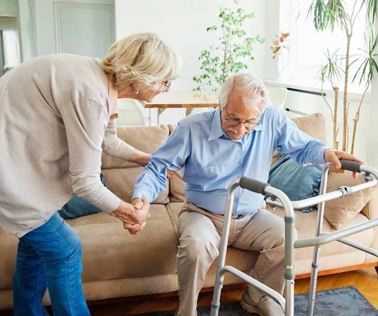 Carer helping elderly gentleman with walking frame